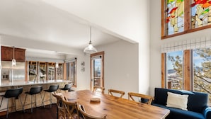 Una cocina amplia con una mesa de comedor de madera, sillas negras y un sofá azul con un cojín blanco.