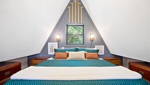 Une chambre à coucher avec un lit, des tables de chevet, une fenêtre et des lampes fixées au mur.