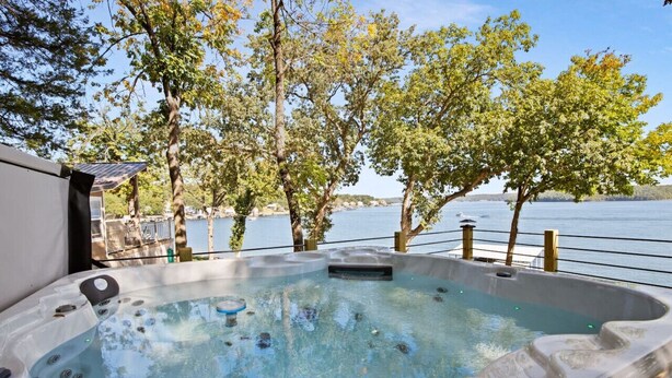 Un bain à remous offrant une vue dégagée sur un lac et des arbres en arrière-plan.