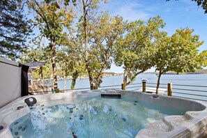 Een hottub met uitzicht op een meer en bomen op de achtergrond.