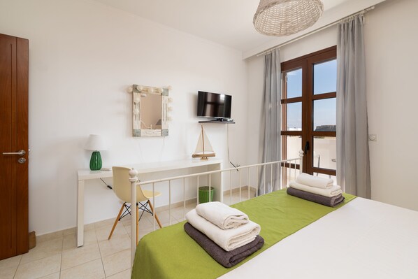 A hotel room with a bed, a desk, a chair, a television, and a window with curtains.