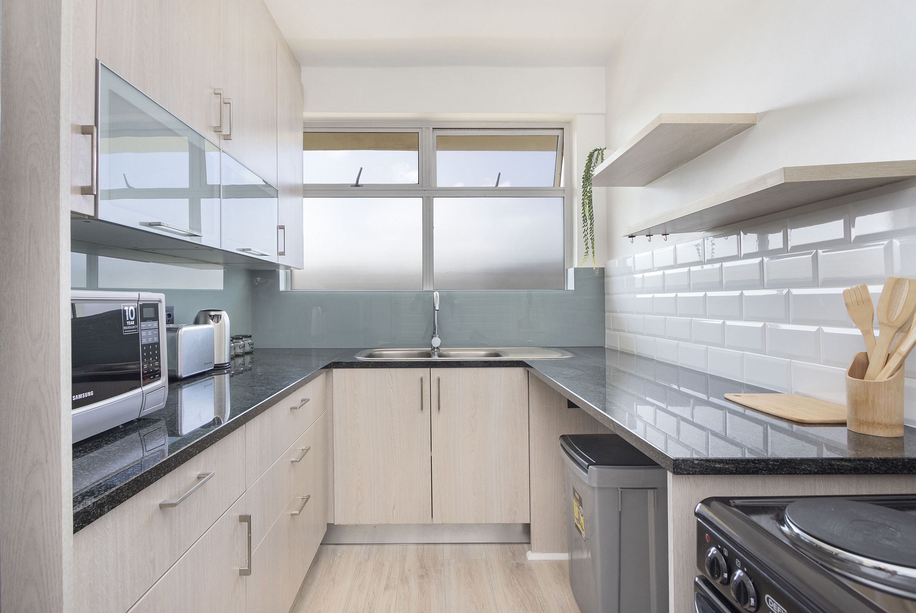 A modern kitchen with a microwave, toaster, sink, and stove.