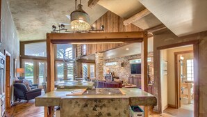 Un amplio salón con una gran mesa de madera, una chimenea y una pared de piedra.