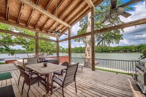 A covered outdoor deck with a table and chairs, overlooking a lake. - Ld 247 Waters Edge At Lake Dunlap 4 Bedroom Home by RedAwning (New Braunfels)