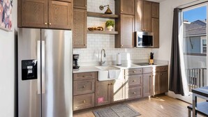 A modern kitchen with wooden cabinets, stainless steel appliances, and a large window with a view.