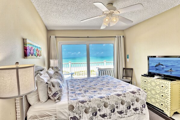 A hotel room with a bed, a TV, a ceiling fan, and a balcony with a view of the ocean. - Beach Front~2 Balconies~Breathtaking Views~Beach Haven C6 (Treasure Island)