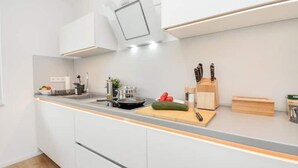 Une cuisine moderne avec des meubles blancs, un plan de travail gris et une cuisinière encastrée.