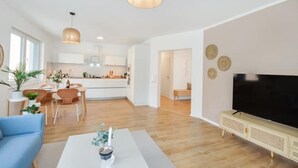 Un salon moderne avec un téléviseur à écran plat, une table basse et un canapé.