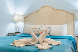 Une chambre d’hôtel avec un lit, une table de chevet, une lampe et un coussin décoratif.