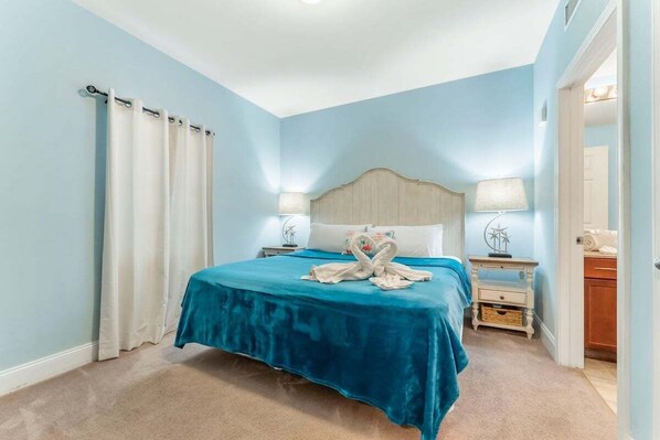 Une chambre à coucher comprenant un lit, deux tables de chevet, une tête de lit et une petite table.