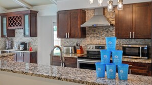 A kitchen with granite countertops, stainless steel appliances, and wooden cabinets. There are blue containers labeled "Jaystays" on the counter.