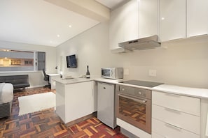 A modern kitchen with white cabinets, a microwave, an oven, and a dishwasher. - Sandringham 55 (Cape Town)