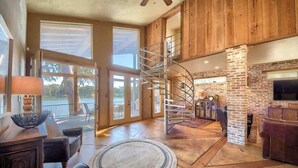 A spacious living area with a spiral staircase, large windows, and a fireplace.