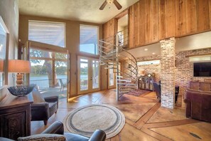 A spacious living area with a spiral staircase, large windows, and a fireplace.