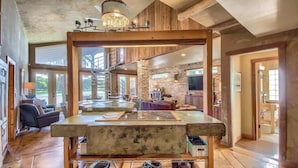 A spacious living area with a large wooden table, a fireplace, and a view of the outdoors.