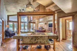A spacious living area with a large wooden table, a fireplace, and a view of the outdoors.