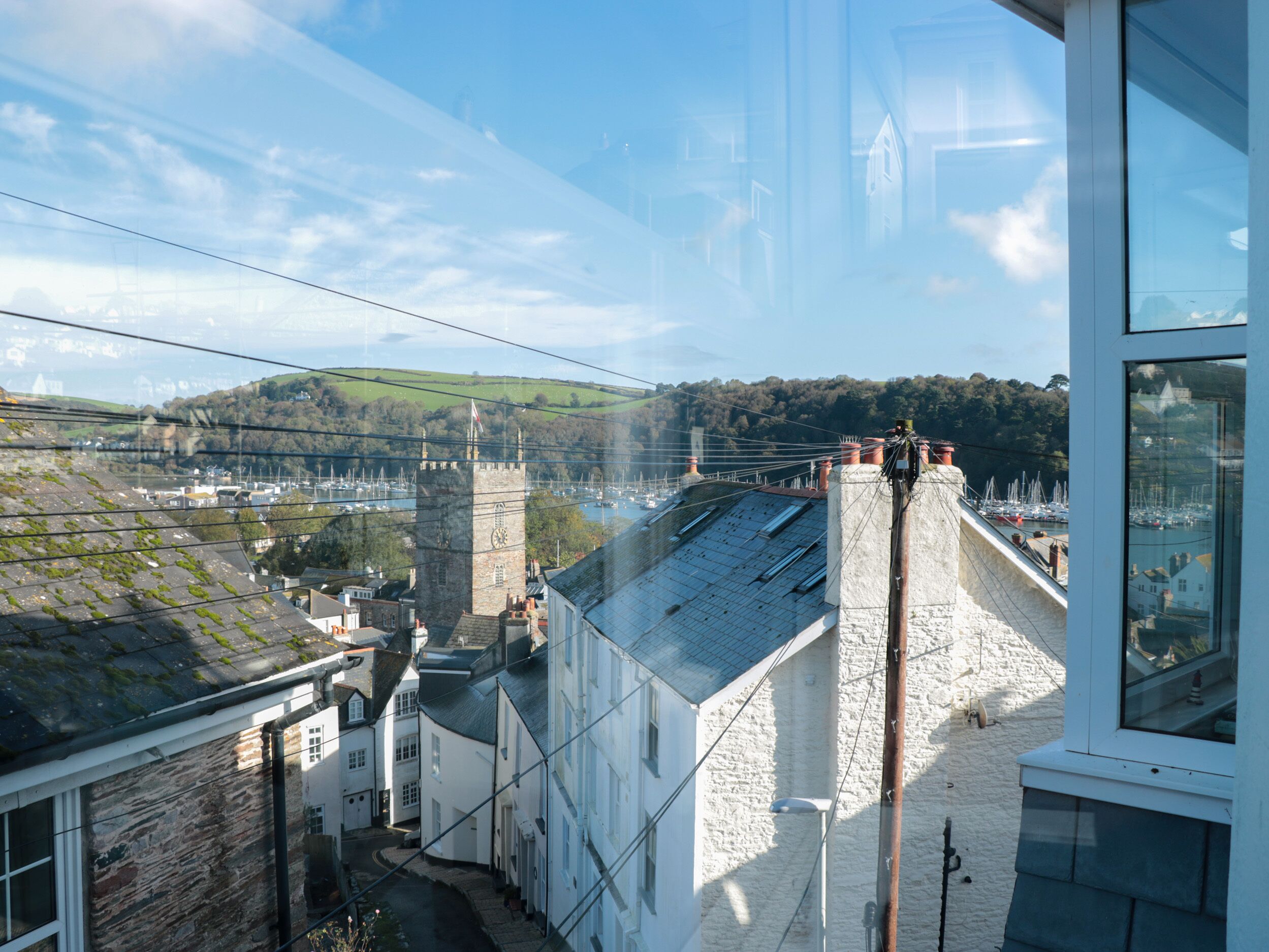 A view from a window overlooking a town with stone buildings, a tower, and a marina.