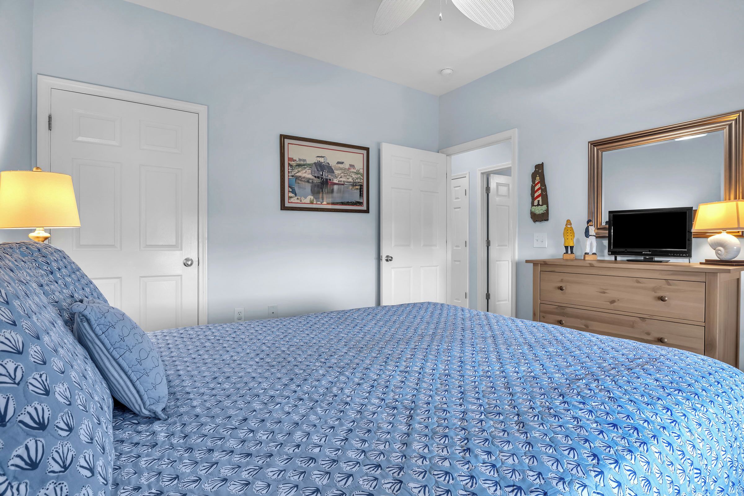 A bedroom with a bed, a dresser, a television, and a framed picture on the wall.
