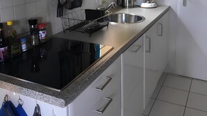 A modern kitchen with white cabinets, a black countertop, and stainless steel appliances.