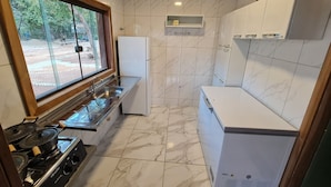 A compact kitchen with a gas stove, a sink, and a refrigerator. - Recanto da Pesca Resort (Abaeté)