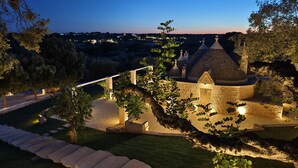 Un edifici de pedra amb diverses teulades còniques, envoltat de camins ben il·luminats i vegetació.