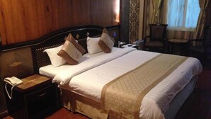 A hotel room with a large bed, a bedside telephone, and a chair near the window. - Inter Park Hotel (Olongapo)