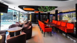 A modern restaurant with red seating, glass walls, and a view of the outdoors. - Inter Park Hotel (Olongapo)