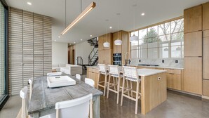 Una cocina moderna con una isla central, armarios de madera e iluminación colgante.