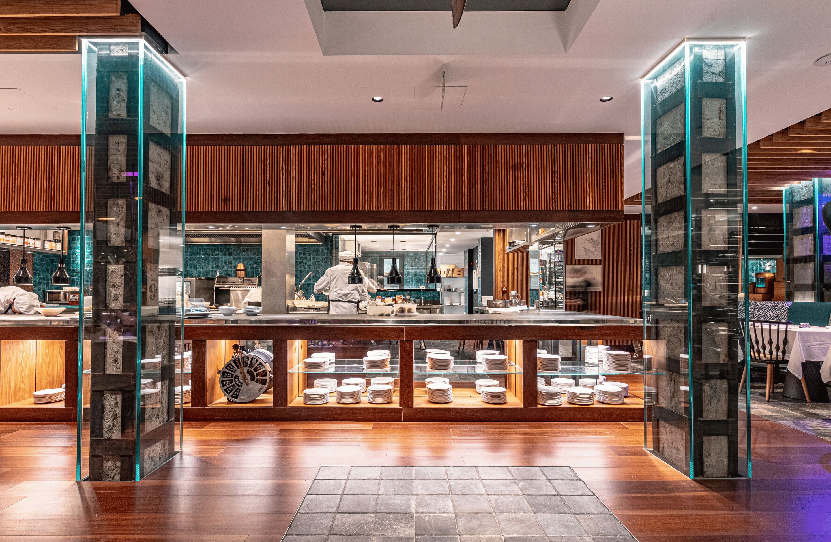 A modern restaurant with a central counter, glass display cases, and wooden paneling.