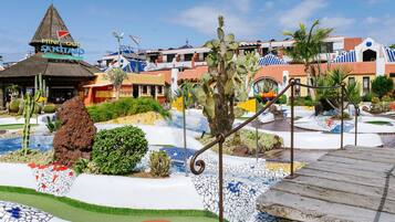 A resort with a pool area, a cactus garden, and a building with a thatched roof.