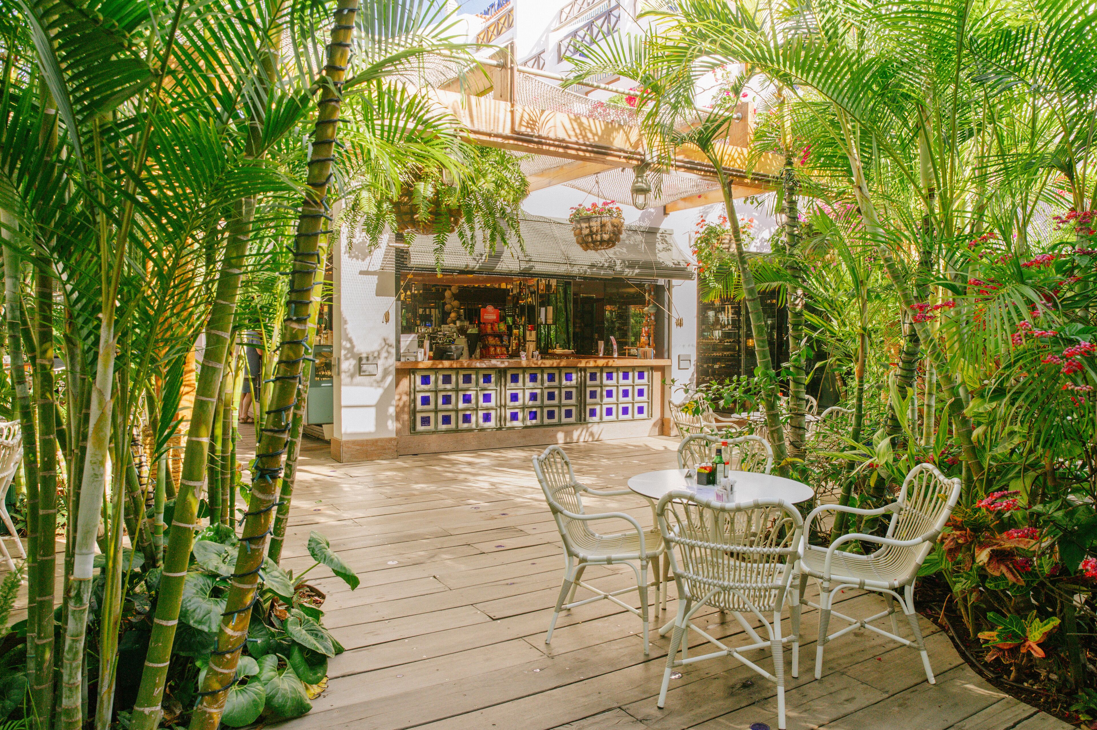 Un área de patio al aire libre con una terraza de madera, sillas de mimbre y una pequeña mesa.