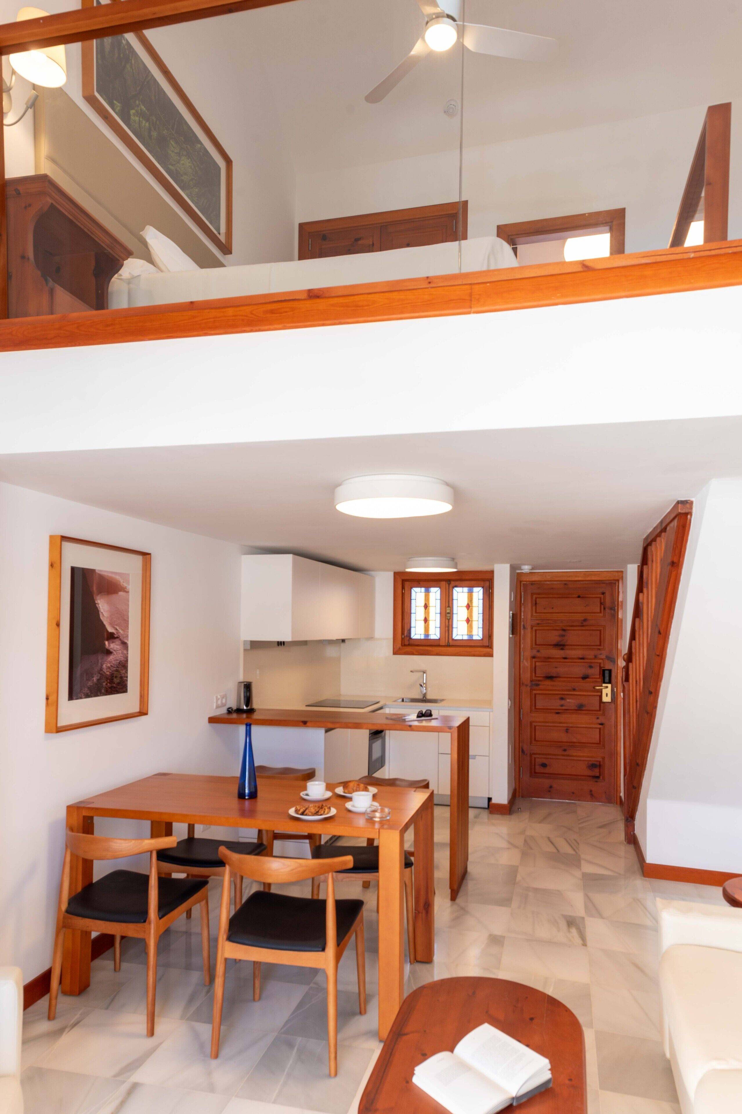 Une cuisine spacieuse avec un coin repas, des meubles en bois et un ventilateur de plafond.