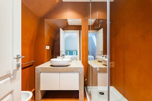 Une salle de bain moderne avec un grand miroir, deux lavabos et une douche.