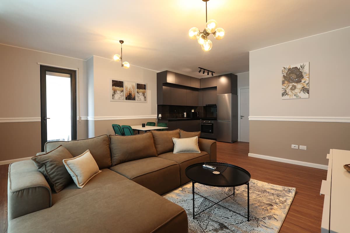 A modern living room with a sectional sofa, a coffee table, and a kitchen in the background.
