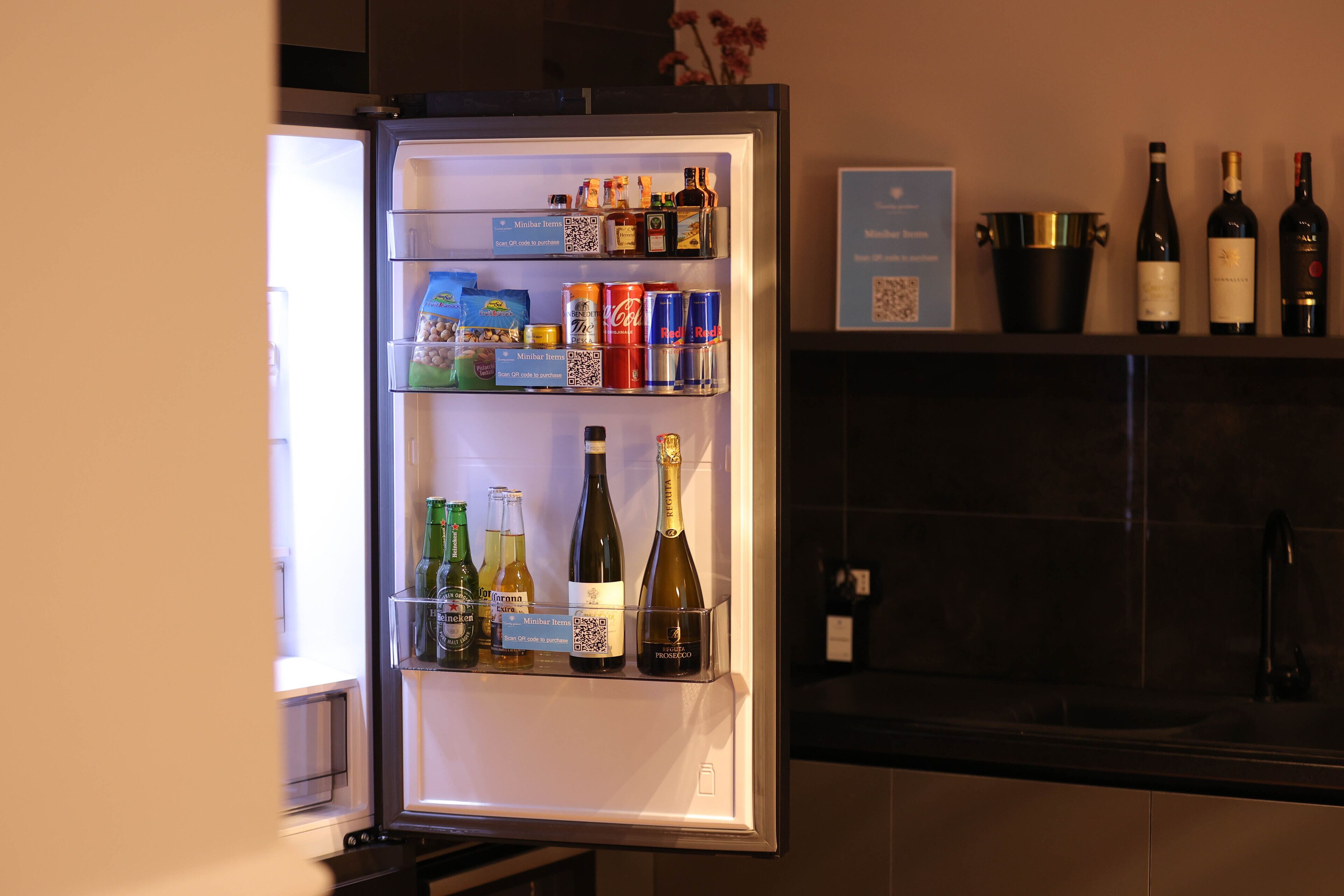 A refrigerator stocked with beverages and snacks, including wine bottles and cans of soda.