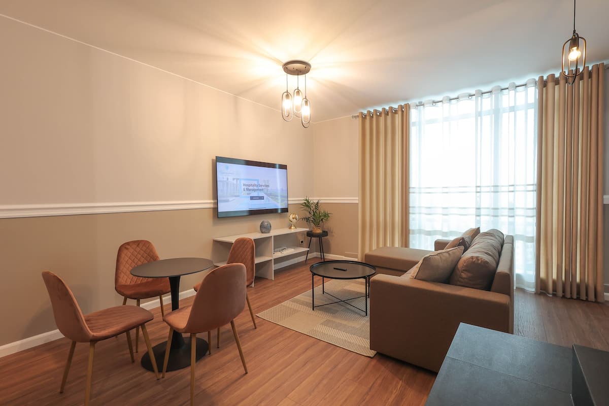 A modern living room with a sofa, chairs, a coffee table, a TV, and a plant.