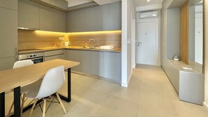 Een moderne keuken met grijze kastjes, een houten aanrecht en een eethoek met een tafel en stoelen.