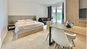Een moderne hotelkamer met een bed, een bank, een eettafel en een keukenhoek.