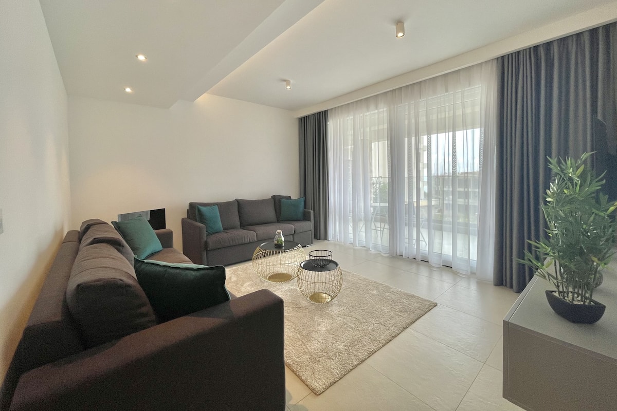A modern living room with a sectional sofa, a coffee table, and a potted plant.