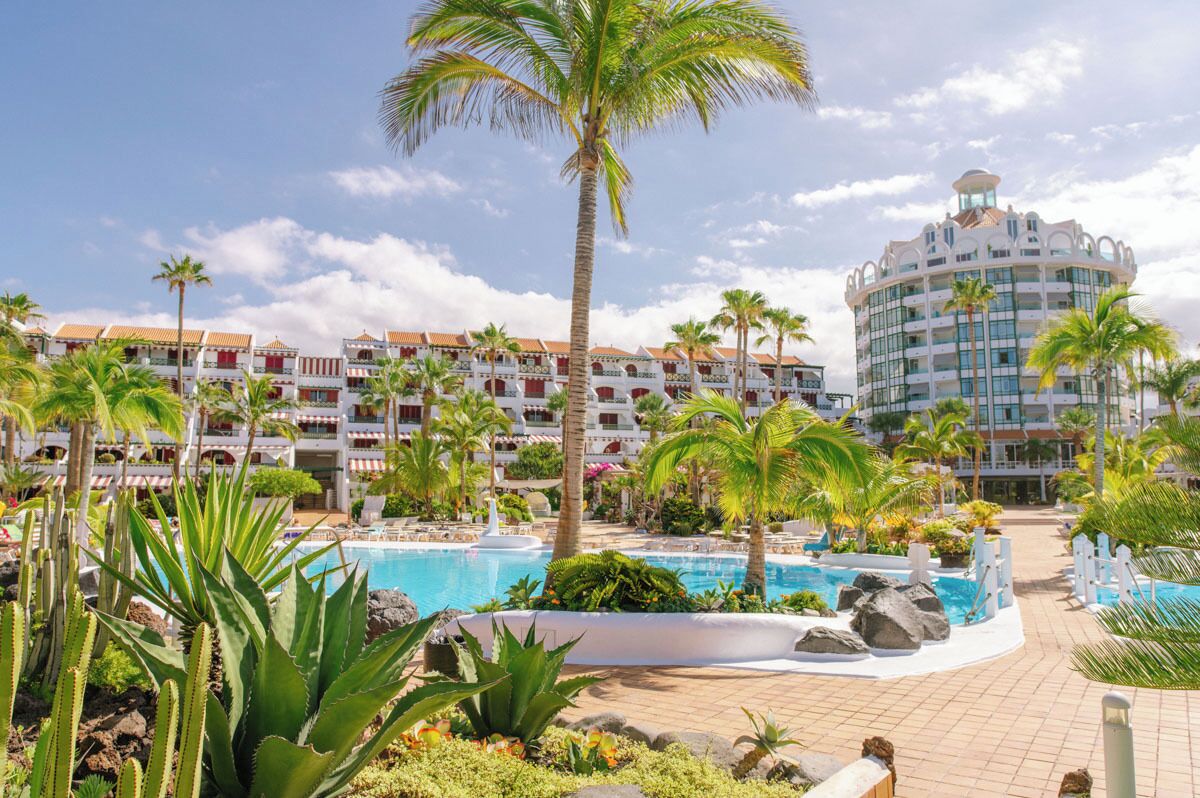A resort with a pool area, palm trees, and a building with a unique architectural design.
