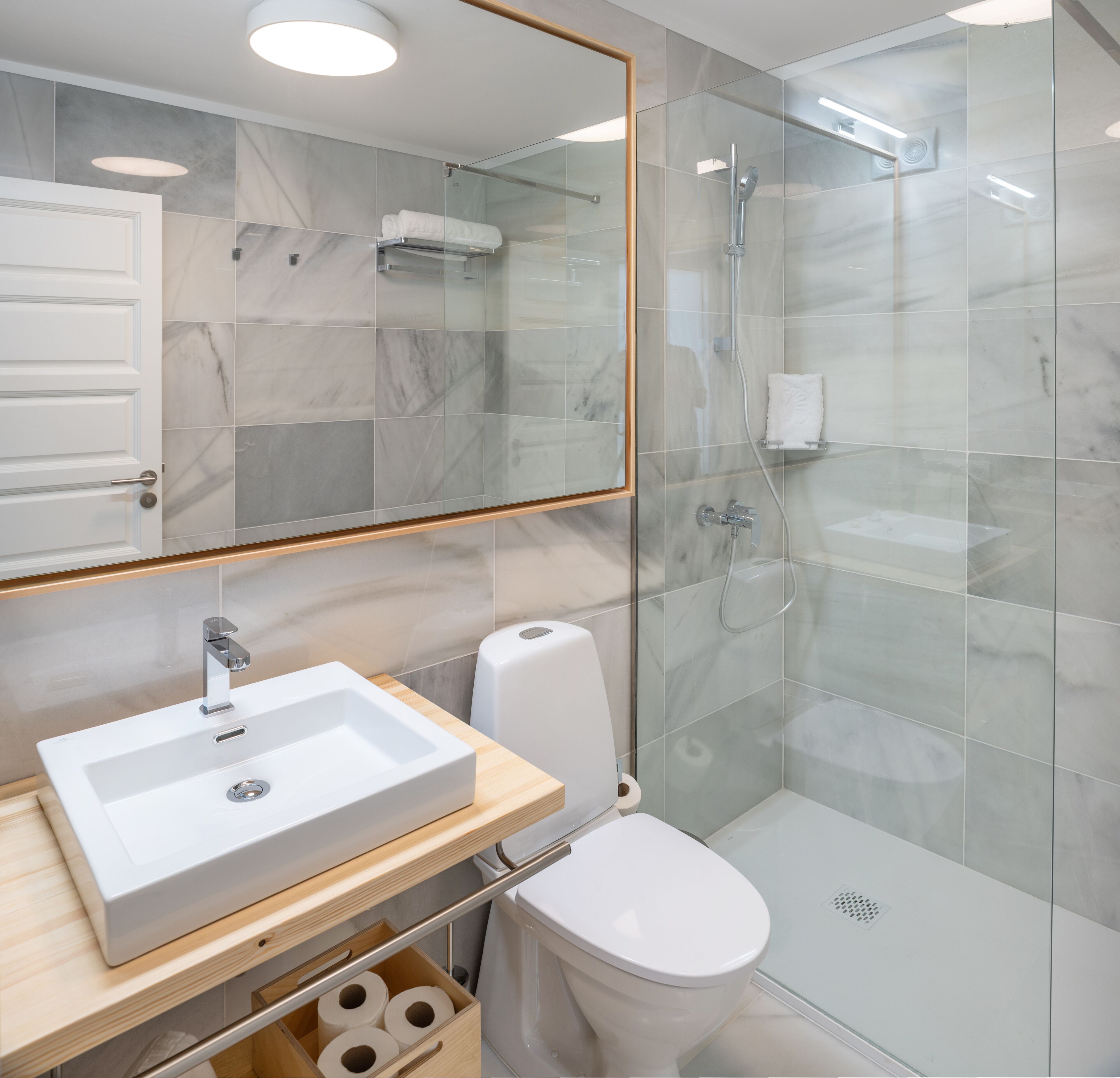 A modern bathroom with a glass shower enclosure, a white sink, and a toilet.