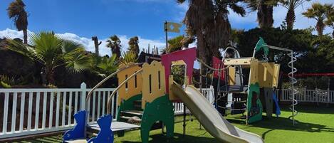 Un parque infantil con tobogán, estructuras para escalar y una zona delimitada.