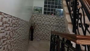 A staircase with a patterned wall, a ceiling light, and a window with artwork. - 2Bedrooms Private. Apart. Junction Mall (Accra)