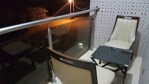 A balcony with a glass table and two chairs, a metal railing, and a tiled wall with a pattern. - 2Bedrooms Private. Apart. Junction Mall (Accra)