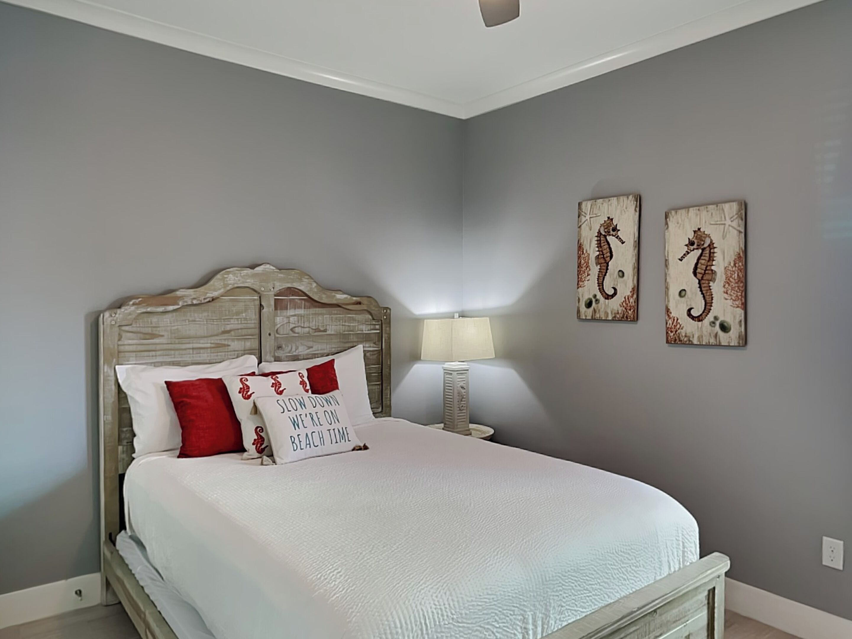 Un dormitorio con una cama, una mesita de noche, una lámpara y dos adornos de caballitos de mar en la pared.