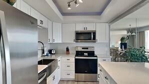 Una cocina moderna con armarios blancos, electrodomésticos de acero inoxidable y una isla central.