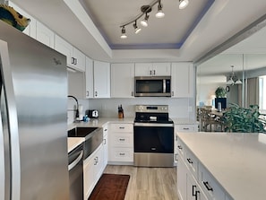 A modern kitchen with white cabinets, stainless steel appliances, and a central island.