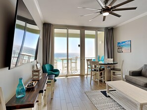 Ein geräumiges Zimmer mit Balkon und Meerblick, einem Deckenventilator, einem Essbereich und einer Couch.