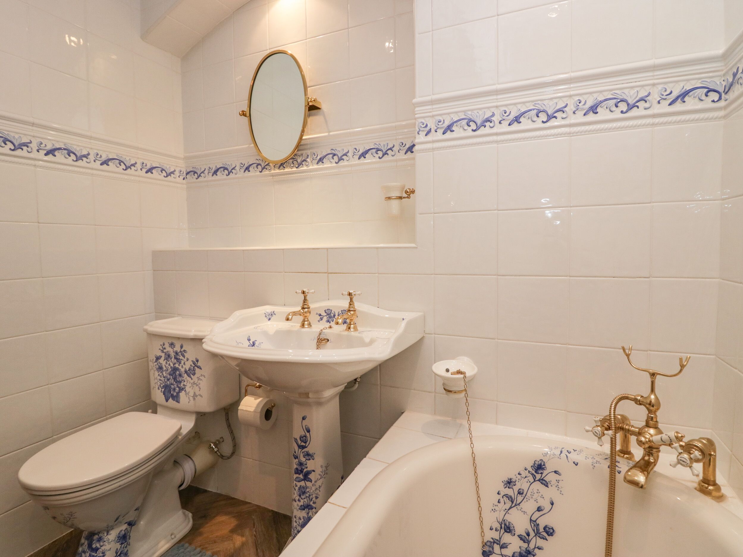 A bathroom with a toilet, sink, and bathtub, all with blue floral patterns.