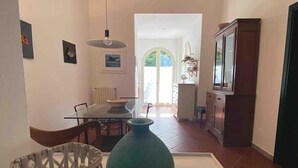 A modern living room with a dining area, a large vase, and a wicker basket on a white table. - Villetta a Castiglioncello (Rosignano Solvay-Castiglioncello)